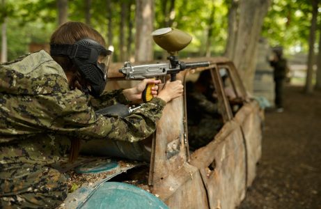 Paintball la Vall Lasertag, paintball en exteriores cerca de La Llosa. Persona disparando desde el coche deteriorado del campo de paintball.